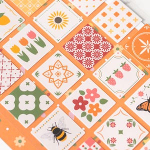 Może przedstawiać: Arkusz dekoracyjnych naklejek z powtarzającym się wzorem kwadratowych płytek. Każda płytka ma inny wzór, w tym kwiaty, owoce i kształty geometryczne. Paleta kolorów obejmuje pomarańczowy, biały, zielony i czerwony.