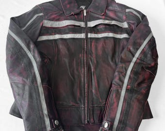 May include: A distressed burgundy leather jacket with silver stripes across the chest and arms. The jacket features a full zip, a collared neckline, and buttoned cuffs. The leather has a worn, vintage appearance.