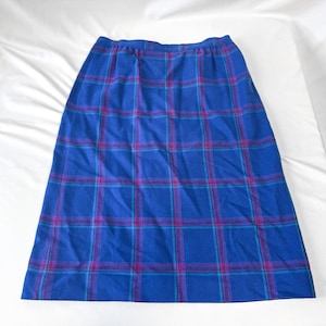 May include: A blue plaid skirt with a straight silhouette. The skirt features a classic plaid pattern in shades of blue, teal, and magenta. The fabric appears to be a medium-weight material, suitable for cooler weather. The skirt is laid flat on a white surface.