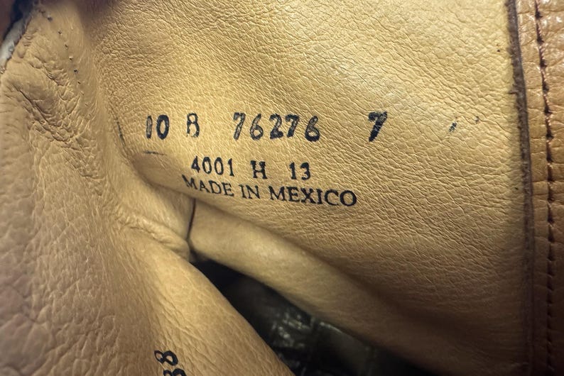 May include: Close-up of the inside of a leather boot. The boot's interior is a light tan color, with visible stitching and texture. Black text includes numbers and the words "MADE IN MEXICO".
