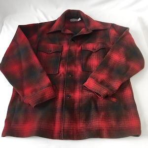 May include: A red and black plaid wool shirt jacket with two chest pockets and two lower pockets. The jacket has a button-down front and a collar. The fabric has a classic lumberjack style.