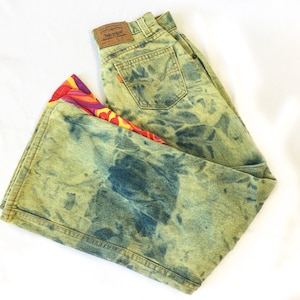 May include: Green, blue, and yellow tie-dye flared jeans with a colorful patterned fabric trim. The jeans have a Levi's brand label.