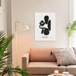 May include: Black and white abstract art print with the word "Vacarely" in cursive at the bottom. The print is framed and hanging on a white wall above a light brown couch.