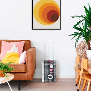 May include: A framed print with a Bauhaus design featuring a series of concentric circles in shades of orange, yellow, and brown. The print has the text "BAUHHAUS" and "INSTITUT F&Uuml;R GESTALTUNG" in black.