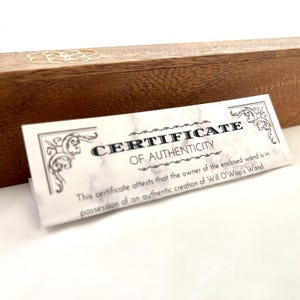 May include: A wooden box with a gold emblem and a certificate of authenticity. The certificate reads "CERTIFICATE OF AUTHENTICITY" and states the wand is an authentic creation of Will O'Wisp's Wand.