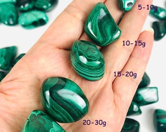 May include: A variety of green malachite tumbled stones of different sizes. The stones are arranged in a hand, with the largest stone at the bottom and the smallest stone at the top. The stones are labeled with their approximate weight in grams: 5-10g, 10-15g, 15-20g, 20-30g, and 30g+.