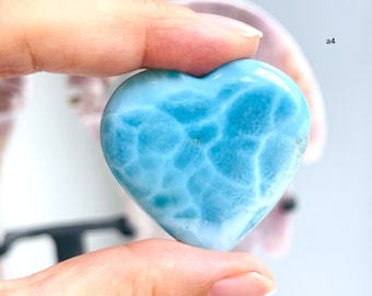 May include: A light blue heart-shaped piece of blue lace agate. The stone has a swirling pattern of white and blue.