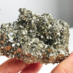 May include: A large, golden brown cluster of pyrite crystals. The crystals are tightly packed together and have a metallic sheen.