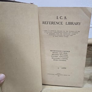 May include: An open vintage book titled "I.C.S. REFERENCE LIBRARY". The pages are aged, displaying text about motor engine castings and foundry appliances. The book is a series of textbooks prepared for students of the International Correspondence Schools.