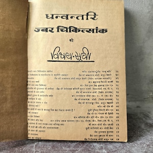 May include: A beige book page featuring black printed text in Hindi. The title reads Dhanvantari Jwar Chikitsank, followed by a table of contents listing various articles, authors, and page numbers in a structured, two-column layout on paper.
