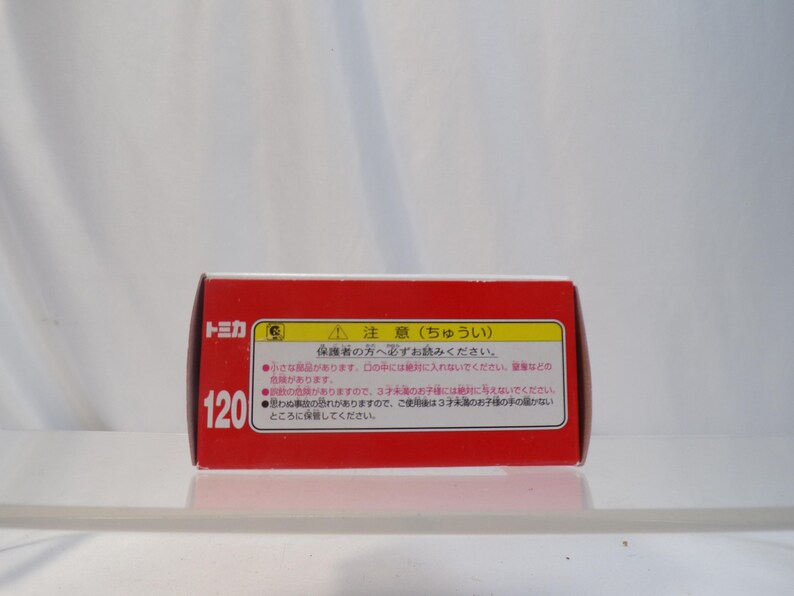 May include: A red rectangular box with Japanese text and the number 120. The box has a white background and a warning label. The text on the box is in Japanese.