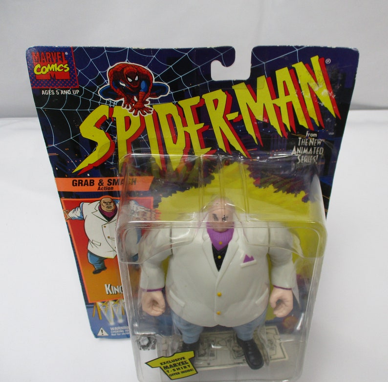 Pu&ograve; includere: Una action figure di Kingpin dalla serie animata di Spider-Man. La figura indossa un abito bianco con una camicia viola e ha la testa rasata. La figura &egrave; confezionata in una confezione blister di plastica con sfondo giallo e rosso. La confezione include le parole "Grab & Smash Action" e "From The New Animated Series!"