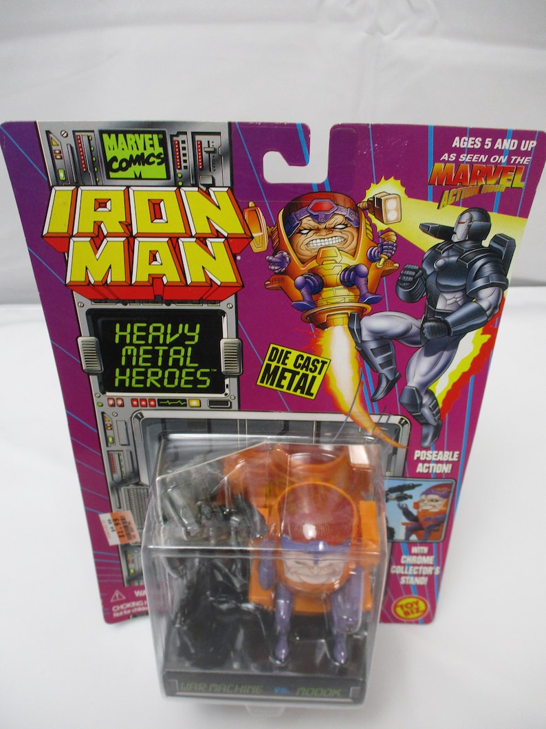 May include: An Iron Man action figure, featuring the character M.O.D.O.K. in a clear plastic case. The packaging is purple and features the Marvel Comics logo and the words "Heavy Metal Heroes". The figure is labeled "War Machine vs. M.O.D.O.K."