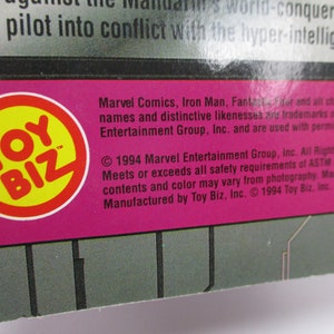 May include: A close-up of a product package with the Toy Biz logo in a yellow circle with a red border. The text includes Marvel Comics, Iron Man, and copyright information from 1994.