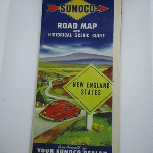 May include: A vintage Sunoco road map and historical scenic guide for New England states. The map features a red car driving on a winding road with a yellow sign that reads "New England States". The map is a collectible item for car enthusiasts and history buffs.