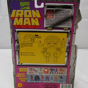 May include: A plastic action figure of the Marvel Comics character Modok, a supervillain with a large head and a robotic body. The figure is posed in a sitting position with his arms outstretched. The figure is packaged in a cardboard box with a yellow background and a picture of Modok on the back. The box also features the Marvel Comics logo and the words "Iron Man".