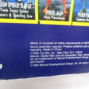 Pu&ograve; includere: Una carta blu e gialla con il testo "Alien Spider Slayer" e "Twin Torso Spider" in un riquadro giallo. Il testo "Pincers & Snarling Jaw" &egrave; anche nel riquadro giallo. La carta presenta anche immagini di Spider-Man e Peter Parker.