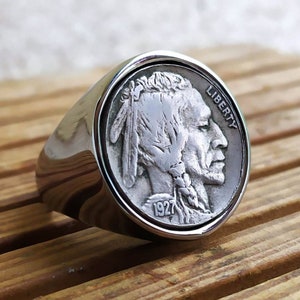 Könnte beinhalten: Silberring mit einem Design einer 1927er Buffalo-Nickel-Münze. Die Münze zeigt ein Profil eines amerikanischen Indianers mit der Aufschrift "LIBERTY" auf der Seite.