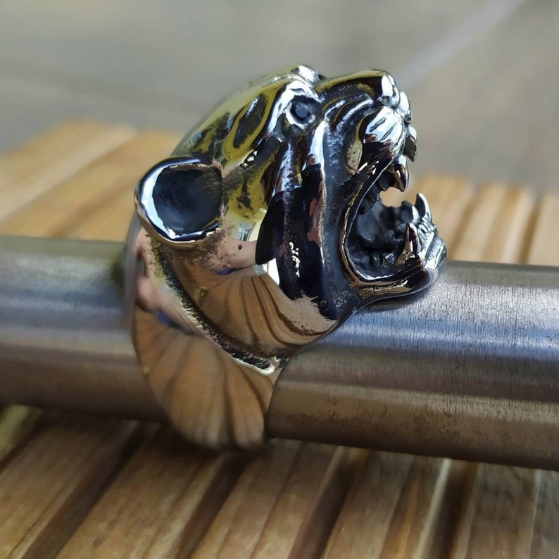 May include: A silver ring featuring a detailed design of a snarling panther head.