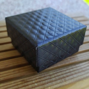 May include: A black gift box with a quilted pattern. The box is made of cardboard and has a smooth, matte finish.