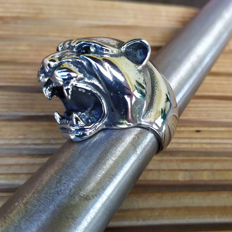 May include: A silver ring featuring a detailed design of a snarling panther head.