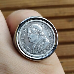 May include: Silver ring with a coin featuring a profile of Pope Pius IX. The coin has the inscription "PIVS IX. P. M. A. XX. II."
