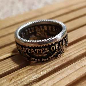 Peut inclure: Une bague en argent et or avec les mots "United States of America" et "E Pluribus Unum" inscrits dessus.
