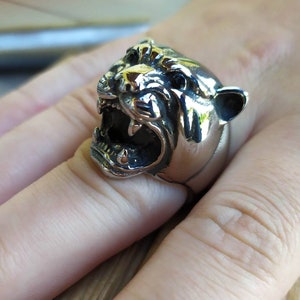 May include: A silver ring featuring a detailed design of a snarling panther head.