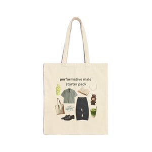 May include: Cream-colored tote bag with the text "performative male starter pack." The bag features illustrations of clothing, accessories, and a drink. Items include a shirt, pants, shoes, a book, a necklace, and a small toy.