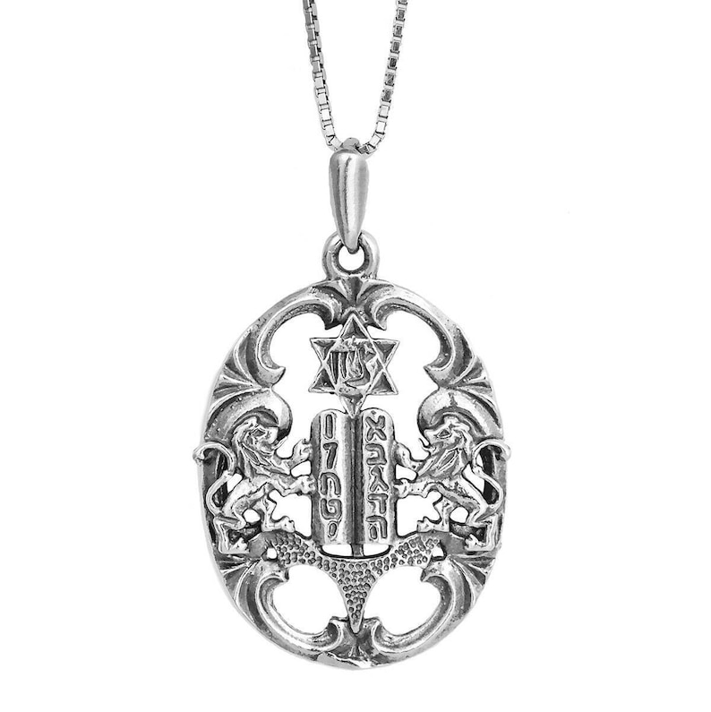 May include: A silver-toned oval pendant on a box chain featuring two lions flanking a central tablet inscribed with Hebrew characters. Above the tablet is a Star of David. The design is openwork with ornate scrollwork details throughout the frame.