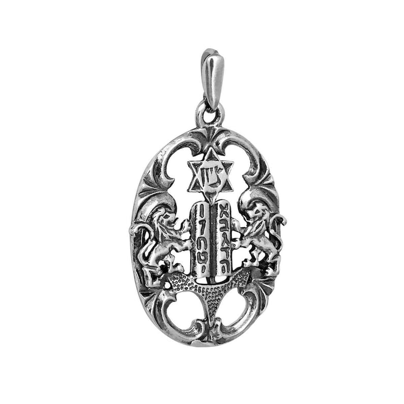 May include: An oval silver pendant featuring two lions standing on either side of the Ten Commandments tablets, which are inscribed with Hebrew characters. Above the tablets is a Star of David. The pendant has an ornate, openwork frame.