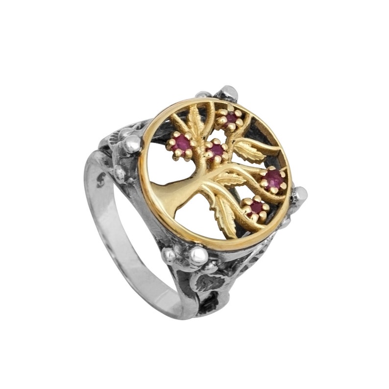 Puede incluir: Un anillo de plata con un dise&ntilde;o de &aacute;rbol de la vida en oro y piedras preciosas rojas. El anillo est&aacute; decorado con tallas intrincadas.