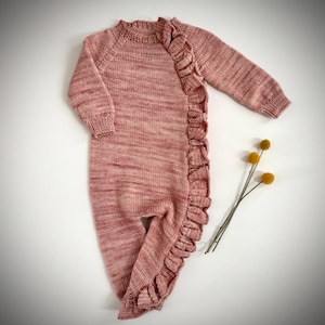 May include: A pink knitted baby onesie with a ruffle detail down the side.