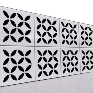 May include: A series of square white tiles arranged in two rows, each featuring a repeating black geometric pattern of four intersecting leaf-shaped petals that form a central diamond and circular motif across the surface of the tiles.