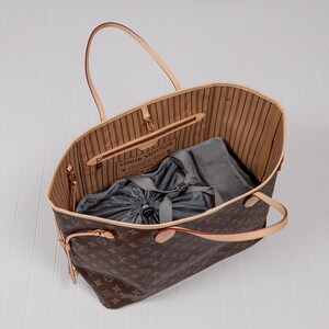 May include: A brown and tan Louis Vuitton tote bag with a gray drawstring bag inside. The bag has a brown leather handle and a gold metal zipper.