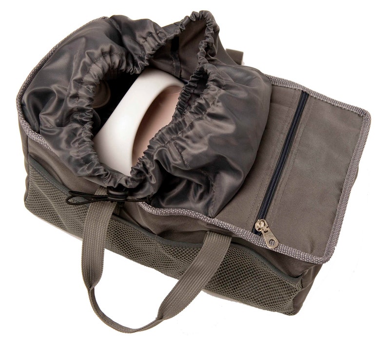May include: A gray canvas bag with a drawstring top and a zippered pocket. The bag has a mesh panel and two handles. The bag is open and a white object is inside.