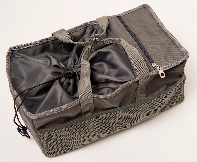 May include: A gray canvas tote bag with a drawstring closure and a mesh pocket on the side. The bag has two top handles and a zippered pocket on the top.