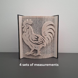May include: A handcrafted book sculpture featuring a rooster design. The rooster is cut from the pages of a book, with the pages forming the body and details. The book is open, with the rooster standing in the center. The text "4 sets of measurements" is at the bottom.