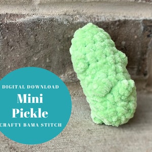 Könnte beinhalten: Ein digitales Download-Muster zum Häkeln eines kleinen grünen Gurkens. Das Muster heißt "Mini Pickle" und ist ein Design von "Crafty Bama Stitch".