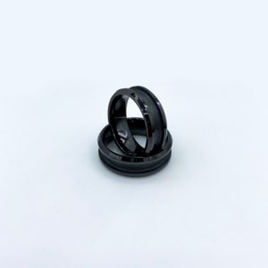 May include: Two black rings with a grooved design. The rings are stacked on top of each other.