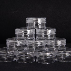 May include: A stack of ten clear plastic containers with a textured rim. The containers are arranged in a pyramid shape.