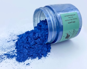 Puede incluir: Un polvo de mica azul en un frasco transparente con una etiqueta blanca que dice "20 Gramos de Polvo de Mica Premium - No Tóxico - Cosmic Dust - Azul".