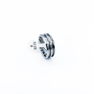 May include: A silver ring with a grooved design. The ring is size 9.