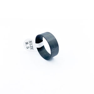 May include: A black carbon fibre ring with a size 9.5 tag attached.