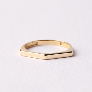 May include: A gold band ring with a hexagonal shape.