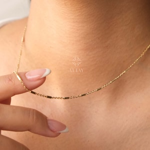 Puede incluir: Un collar de cadena de oro con pequeños eslabones rectangulares. El collar es delicado y sencillo, perfecto para el uso diario.