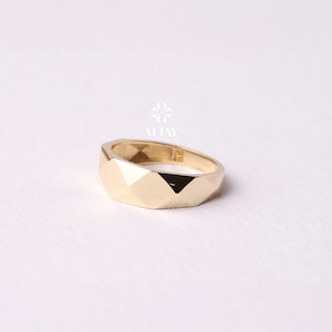 May include: A gold ring with a geometric design. The ring is made of a smooth, shiny metal and has a wide band.