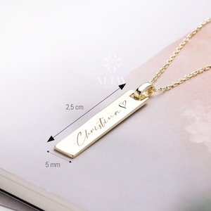 May include: Gold necklace with a personalized bar pendant engraved with the name "Christina" and a small heart symbol. The pendant is 2.5 cm long and 0.5 cm wide.