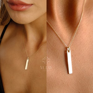May include: A gold chain necklace with a rectangular pendant. The pendant is smooth and has a polished finish.