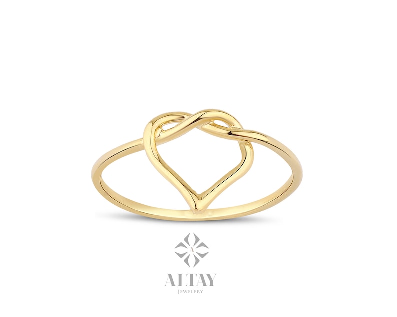 May include: A gold ring with a heart-shaped design. The heart is formed by two intertwined loops of metal.